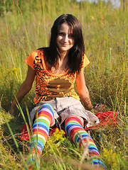 Erotic picture of Wonderful teen beauty in long striped socks taking off her clothes outdoors in the field.