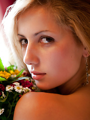 Erotic picture of Amazing teen honey in tempting black stockings posing on bed with a bouquet of flowers.