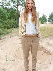 Erotic picture of Delicious teen beauty undressing and spreading her long shapely legs outdoors on the sand.