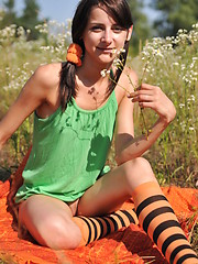 Erotic picture of Marvelous teen girl in striped socks undressing and showing slender body on the nature.