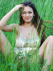 Erotic picture of Sofi A teases her amazing breasts out of her little dress in a field of beautiful green grass.