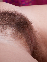 Erotic picture of Vera strips naked in bed showing her hairy pussy